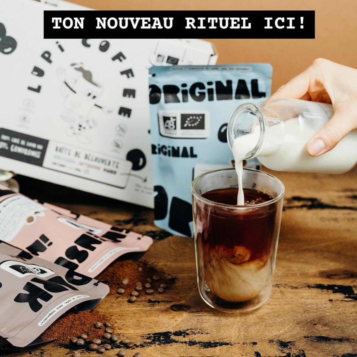 Un café de lupin froid avec du lait sur une table en bois, à côté de la boîte de découverte Lupi Coffee